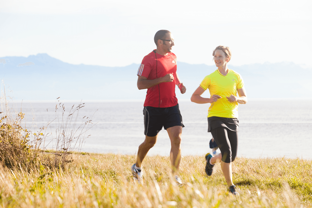 two people running alongside water