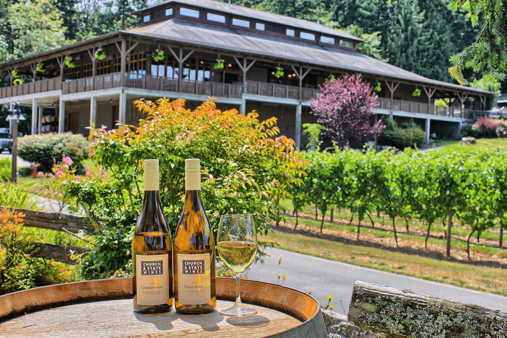 two bottles of wine and a wine glass on a barrel