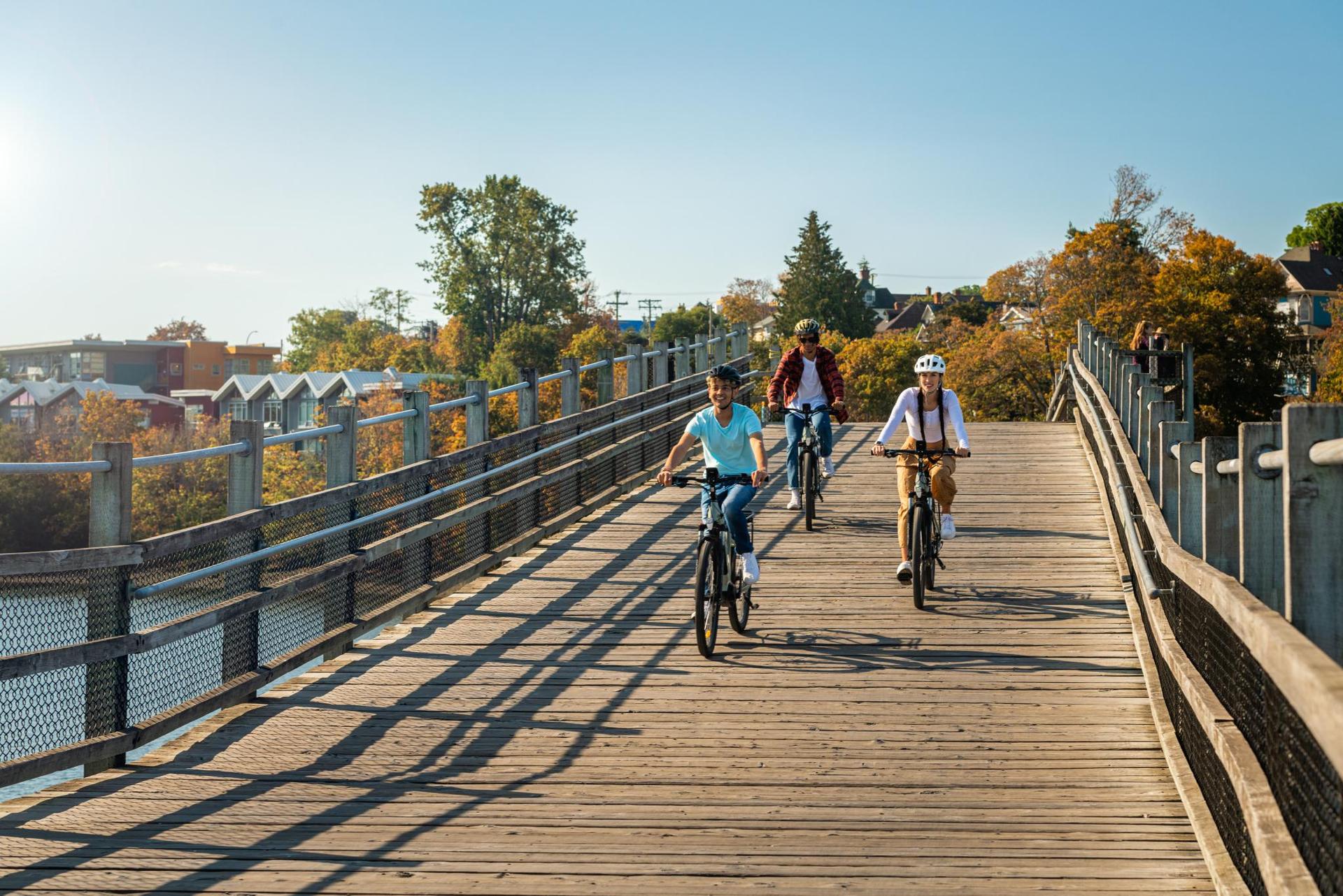 three people bike riding over a wooden bridge