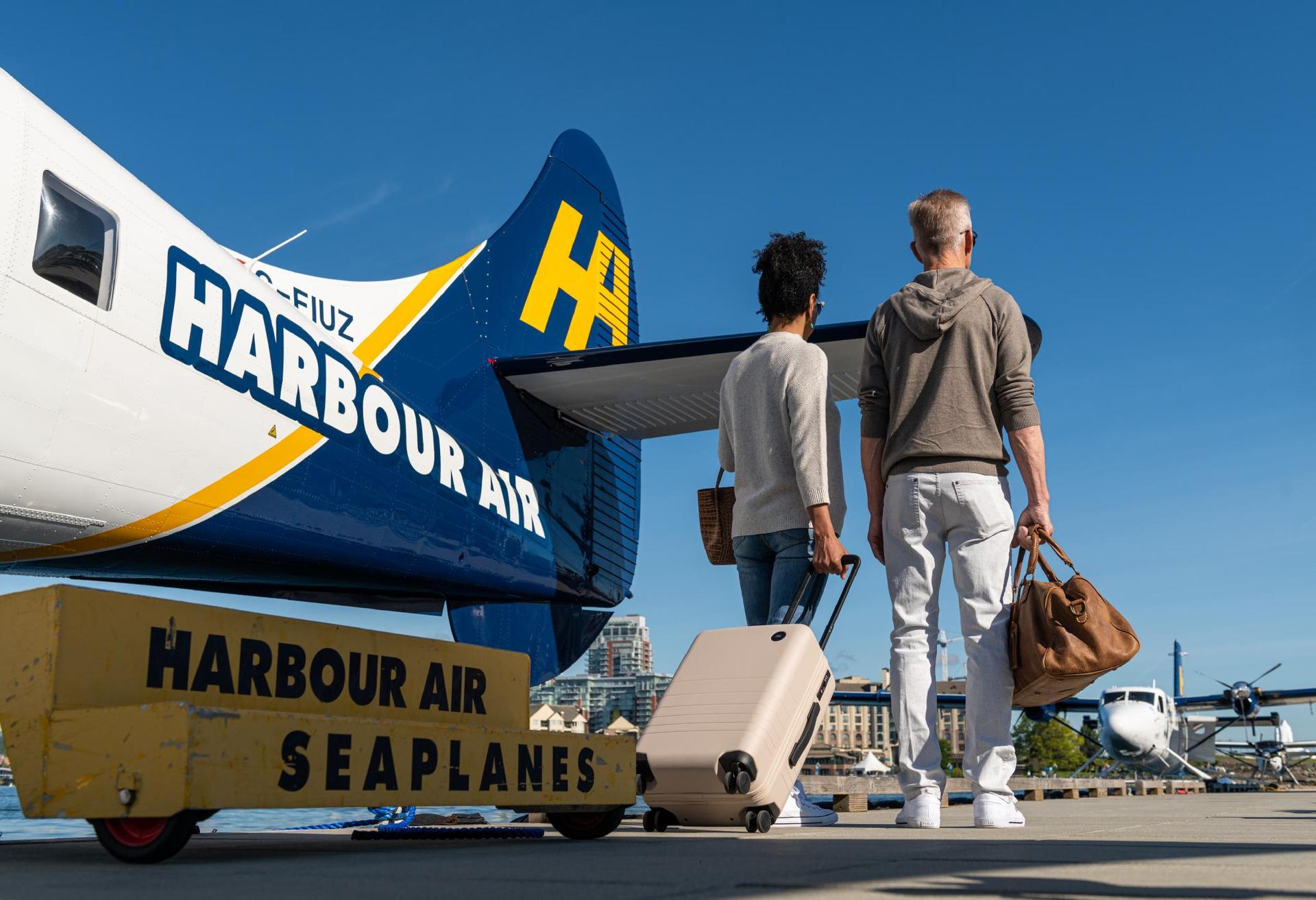 two people walking beside a plane with luggage