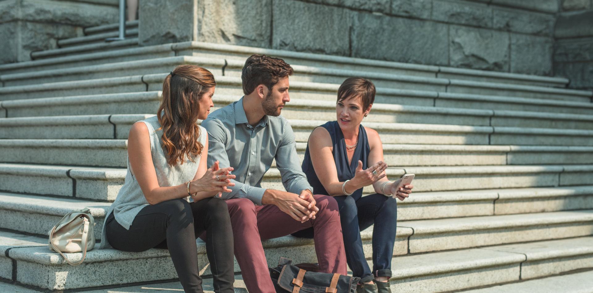 Three people talking on stairs