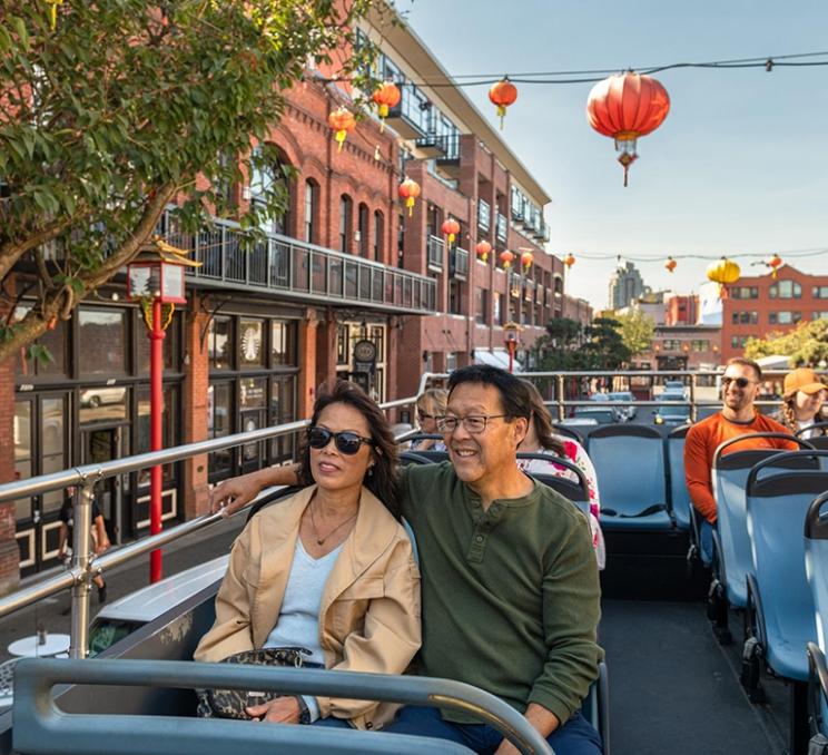 A couple enjoys a hop-on hop-off bus tour through Victoria, BC