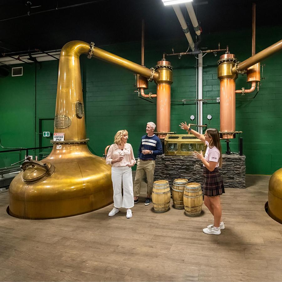 A guide walks a couple through a distillery on a tour in Victoria, BC