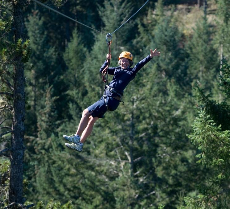 A woman ziplines through the trees in Victoria, BC