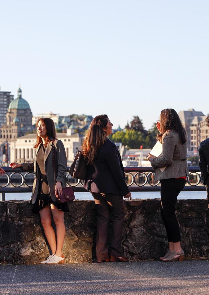 A group of professionals chat on Victoria's Inner Harbour