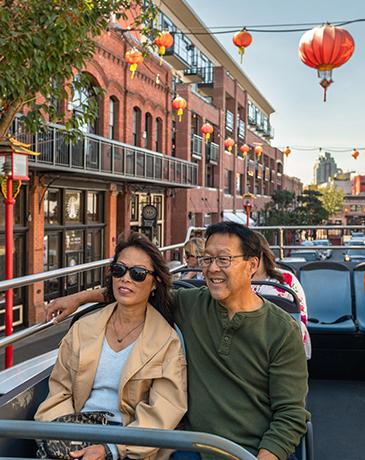 A couple rides a tour bus through Victoria's historic Chinatown