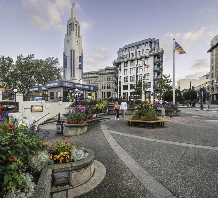 A couple walks past the Victoria Visitor Centre in downtown Victoria, BC